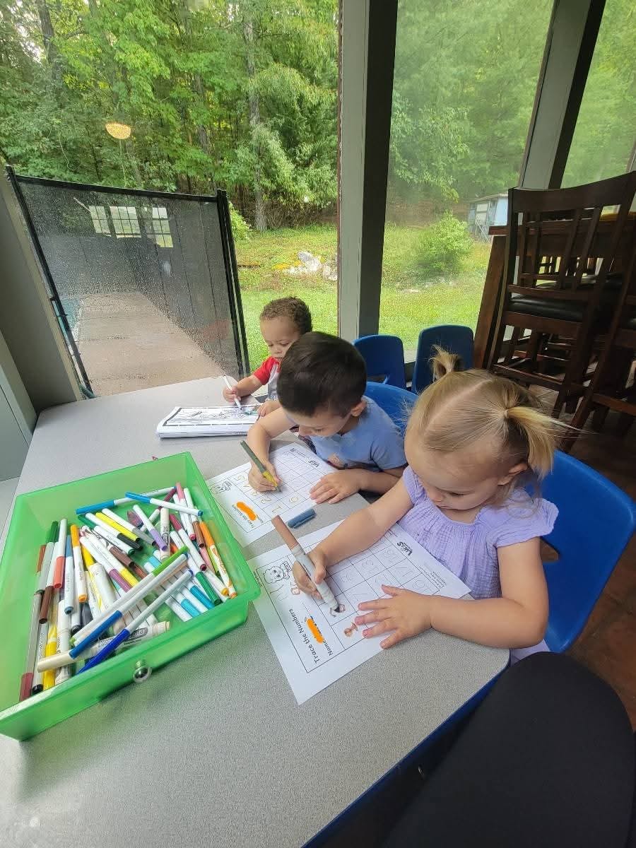Three children drawing at a table with markers