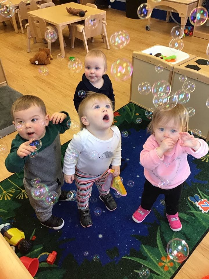 Four children playing with bubbles in a room