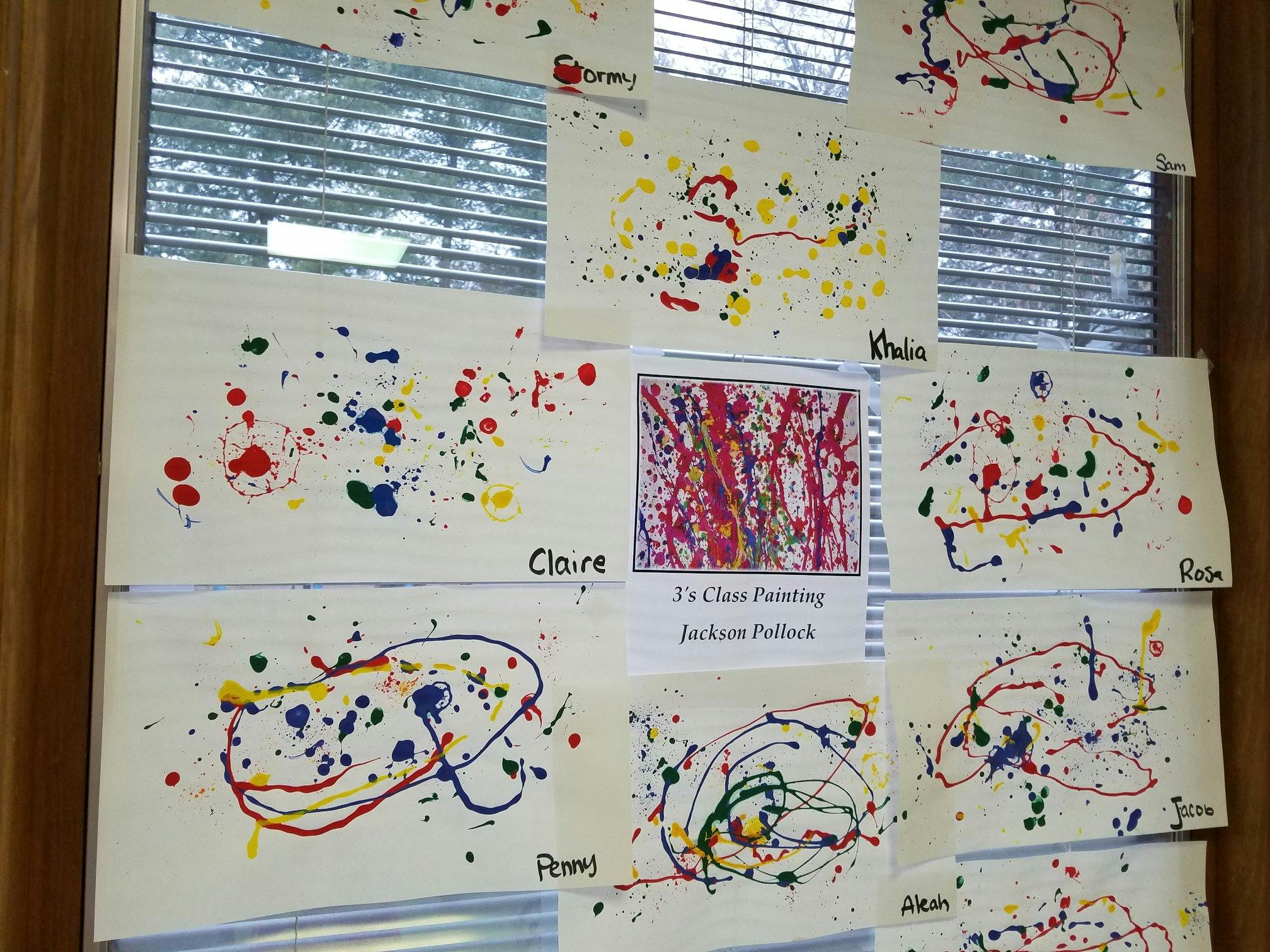 Children's splatter paint artwork displayed on a window