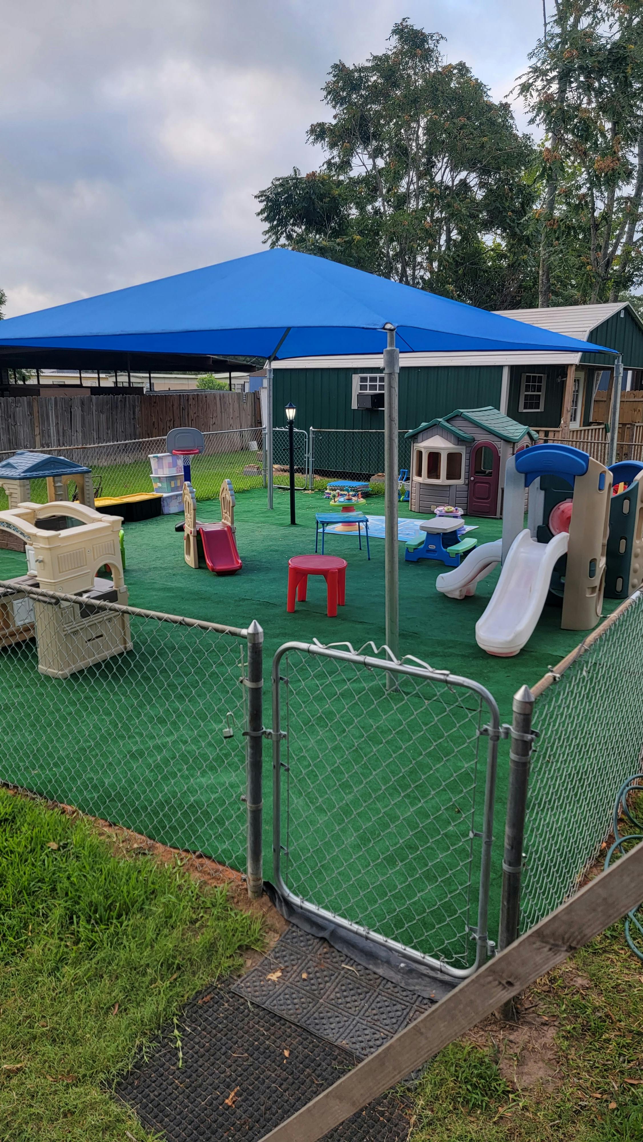 Outdoor playground with slides, playhouses, and a blue shade canopy