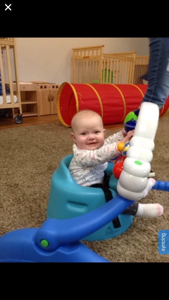 Child in a blue activity seat playing with toys