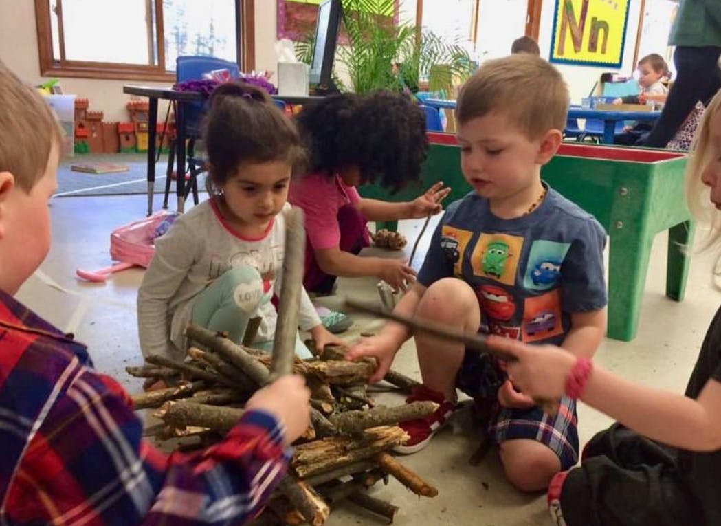 Children playing with sticks in a classroom