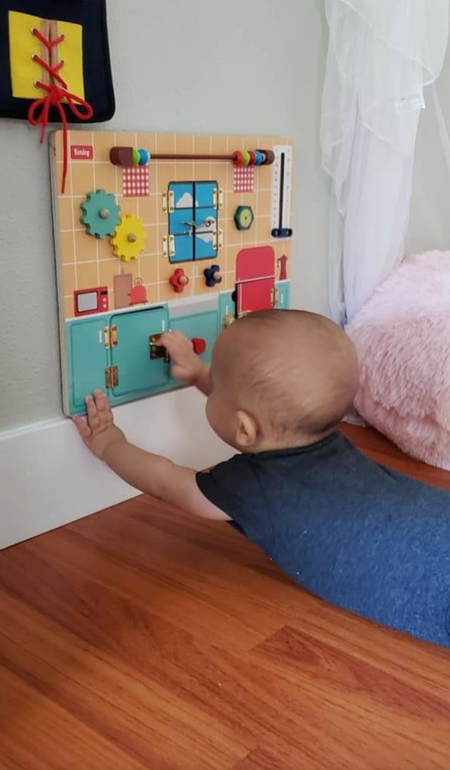 Child playing with a busy board on the floor