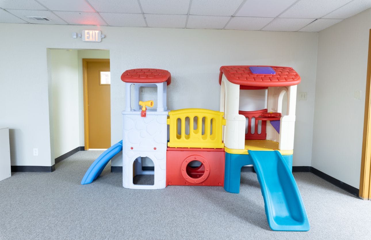 Colorful plastic play structure with slides inside a room