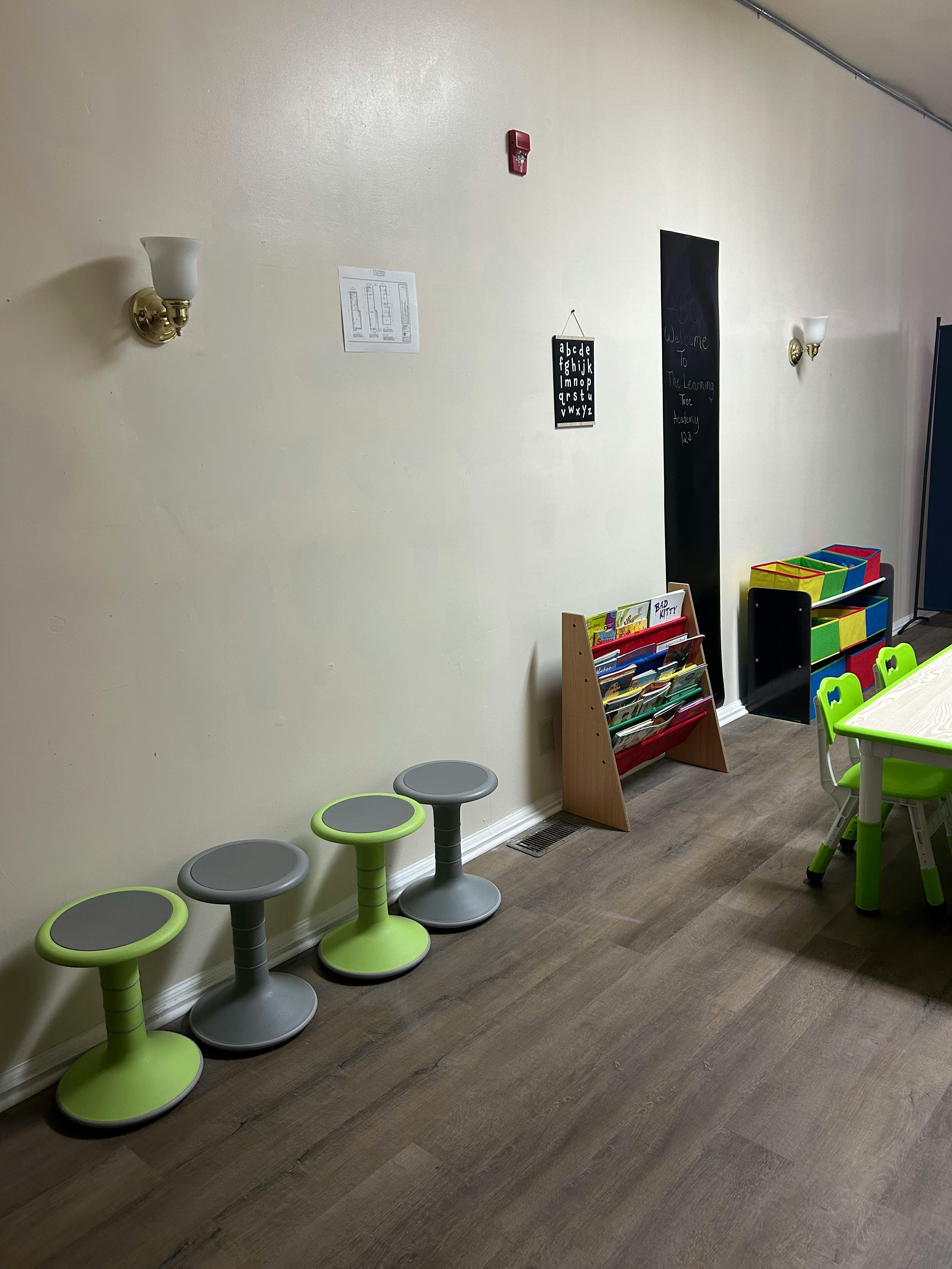Four wobble stools in a classroom with a bookshelf and small table