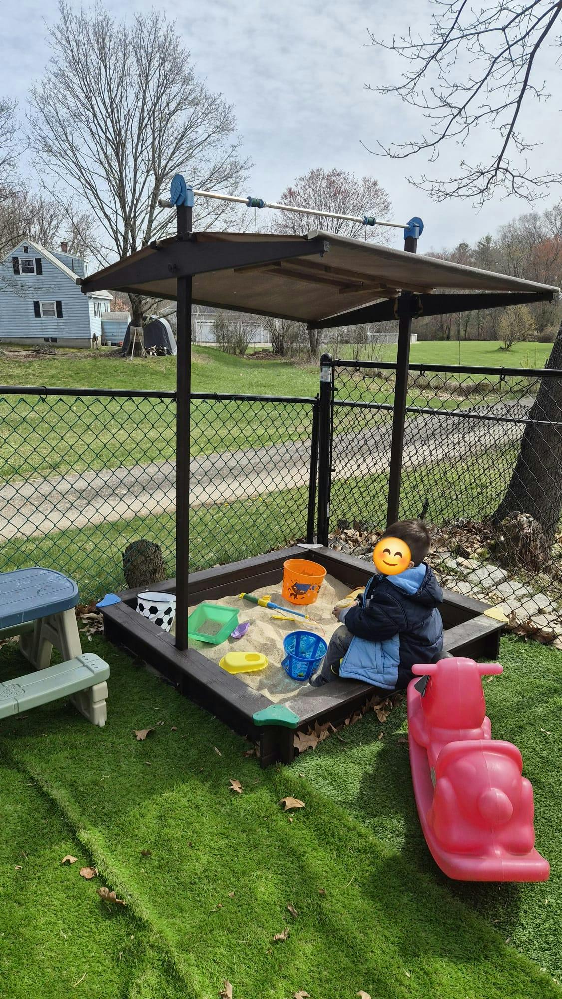 Child playing in a sandbox with various toys