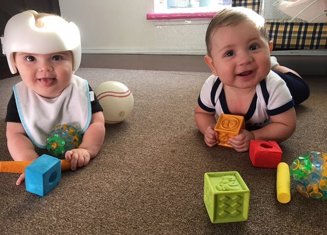 Two babies playing on the floor with toys