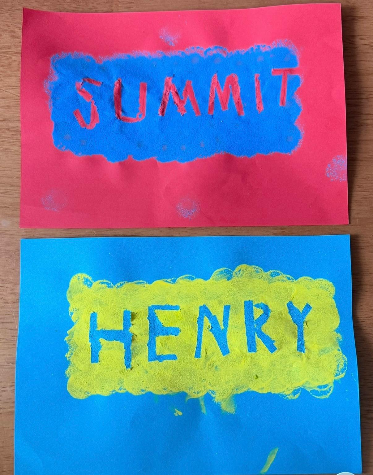 Two paper art pieces with the names Summit and Henry painted on them