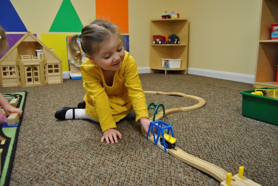 Child playing with a toy train set on the floor
