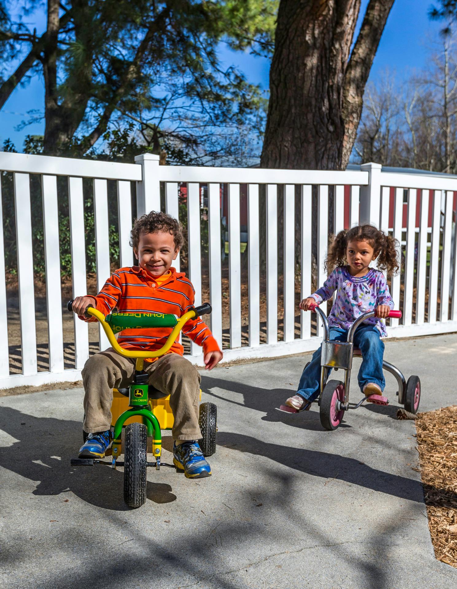 Two children riding tricycles outdoors