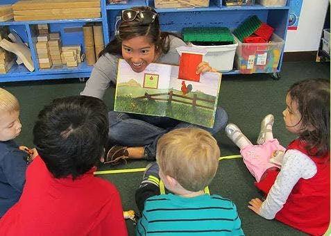 Person reading a book to children sitting on the floor