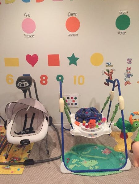 Baby swing and baby bouncer in a room with wall decorations