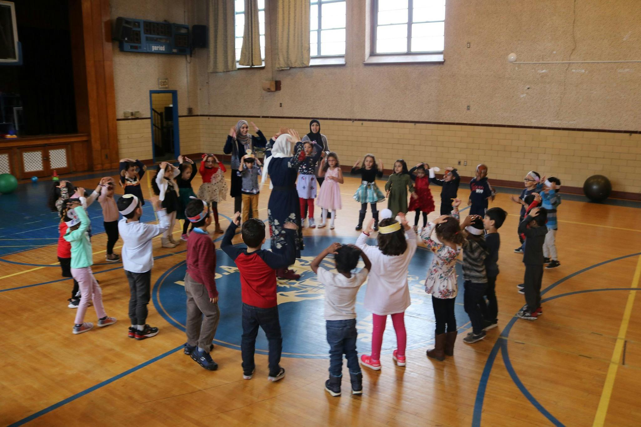 Children and adults in a circle on a gymnasium floor