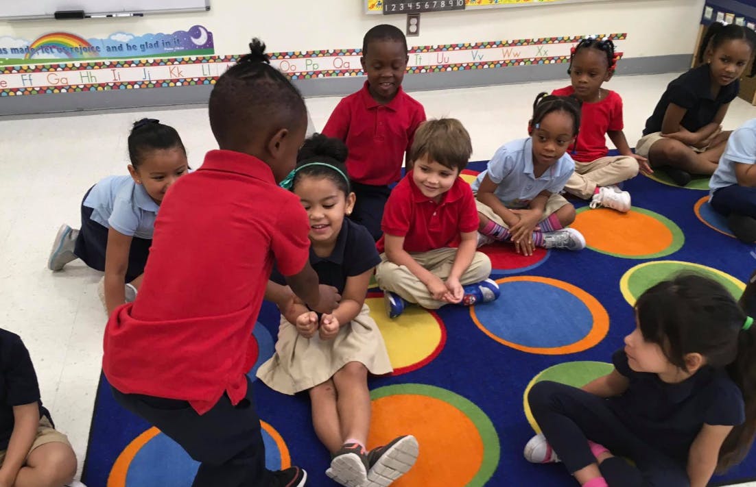Children sitting on a colorful rug in a classroom