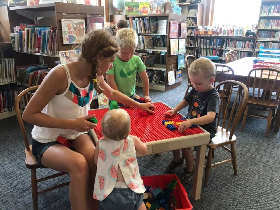 Person and three children playing with building blocks at a table