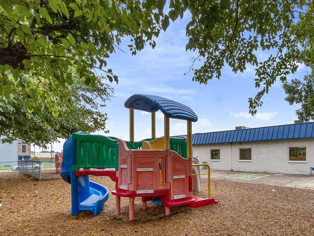 Colorful outdoor playground with slides and a building in the background