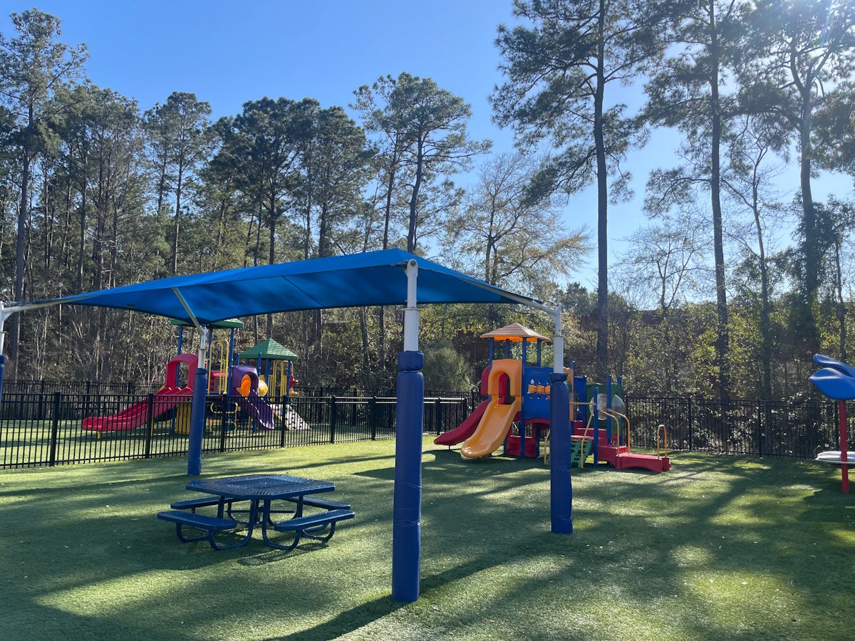 Colorful playground with slides and a picnic table under a blue canopy