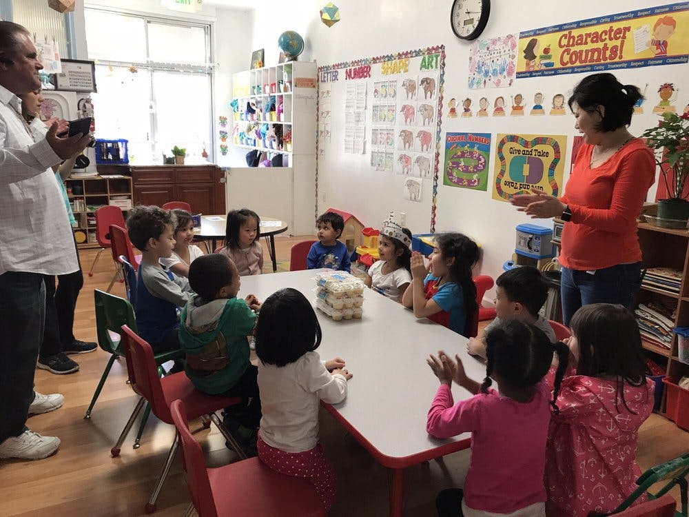 Adults and children gathered around a table in a classroom