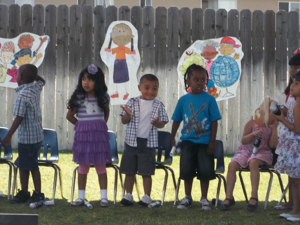 Children standing in front of a fence with paper cutouts