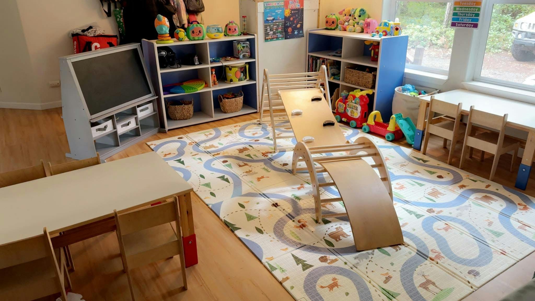Playroom with a climbing arch, tables, chairs, and shelves