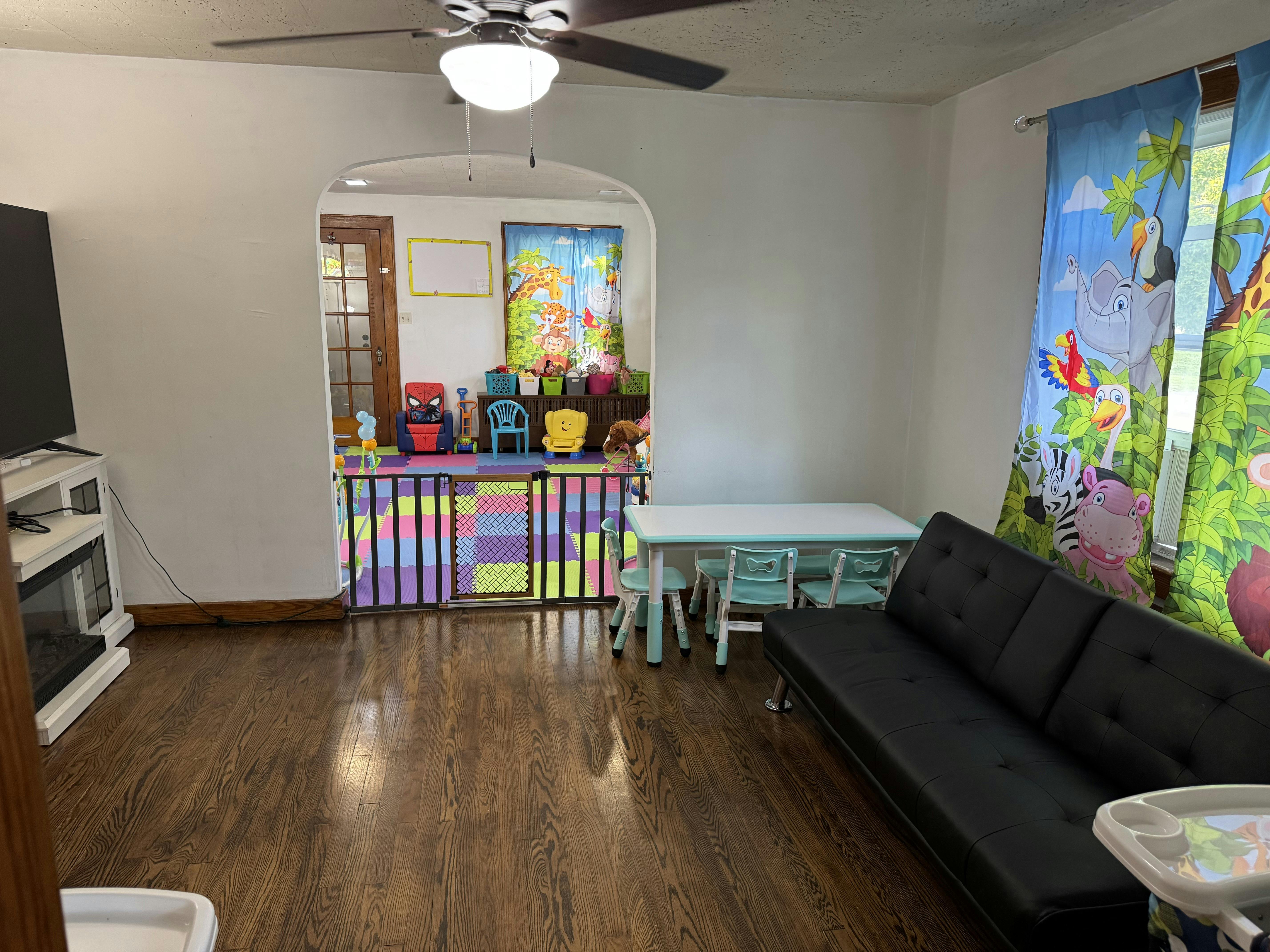 Living room with a black futon, small table and chairs, and a play area