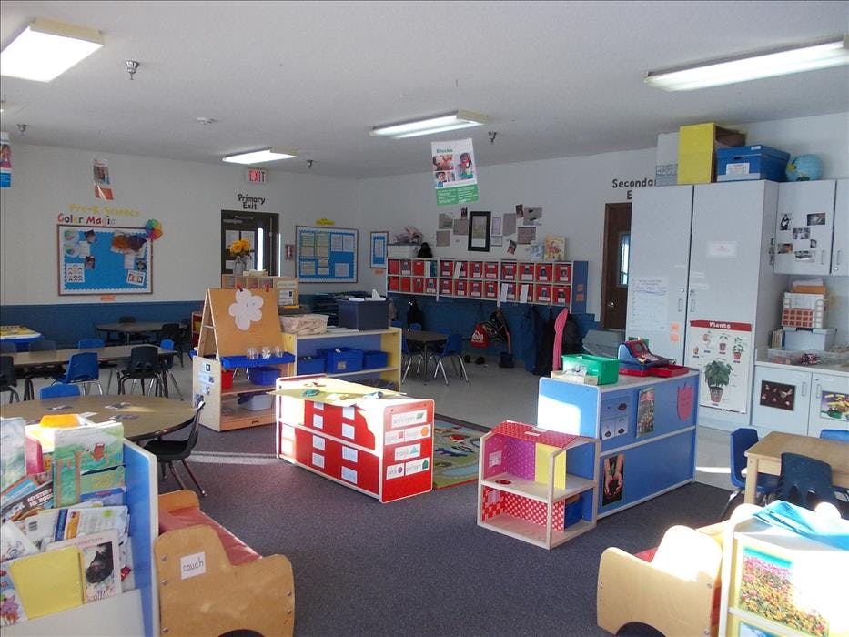 An empty early childhood classroom with various activity centers and tables