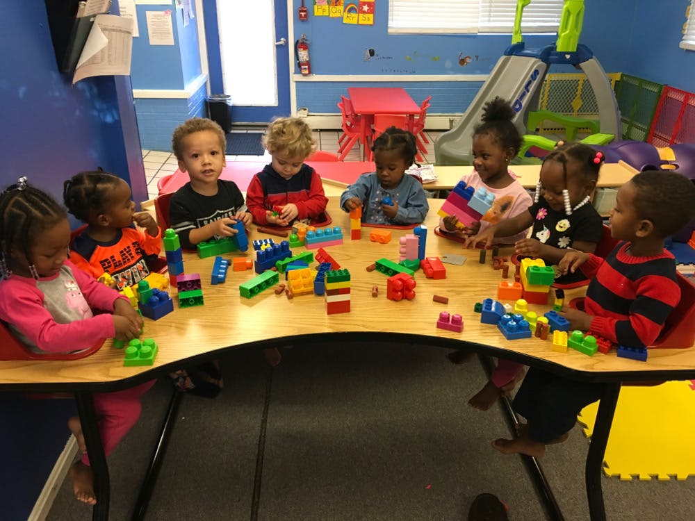 Children playing with building blocks at a table in a classroom