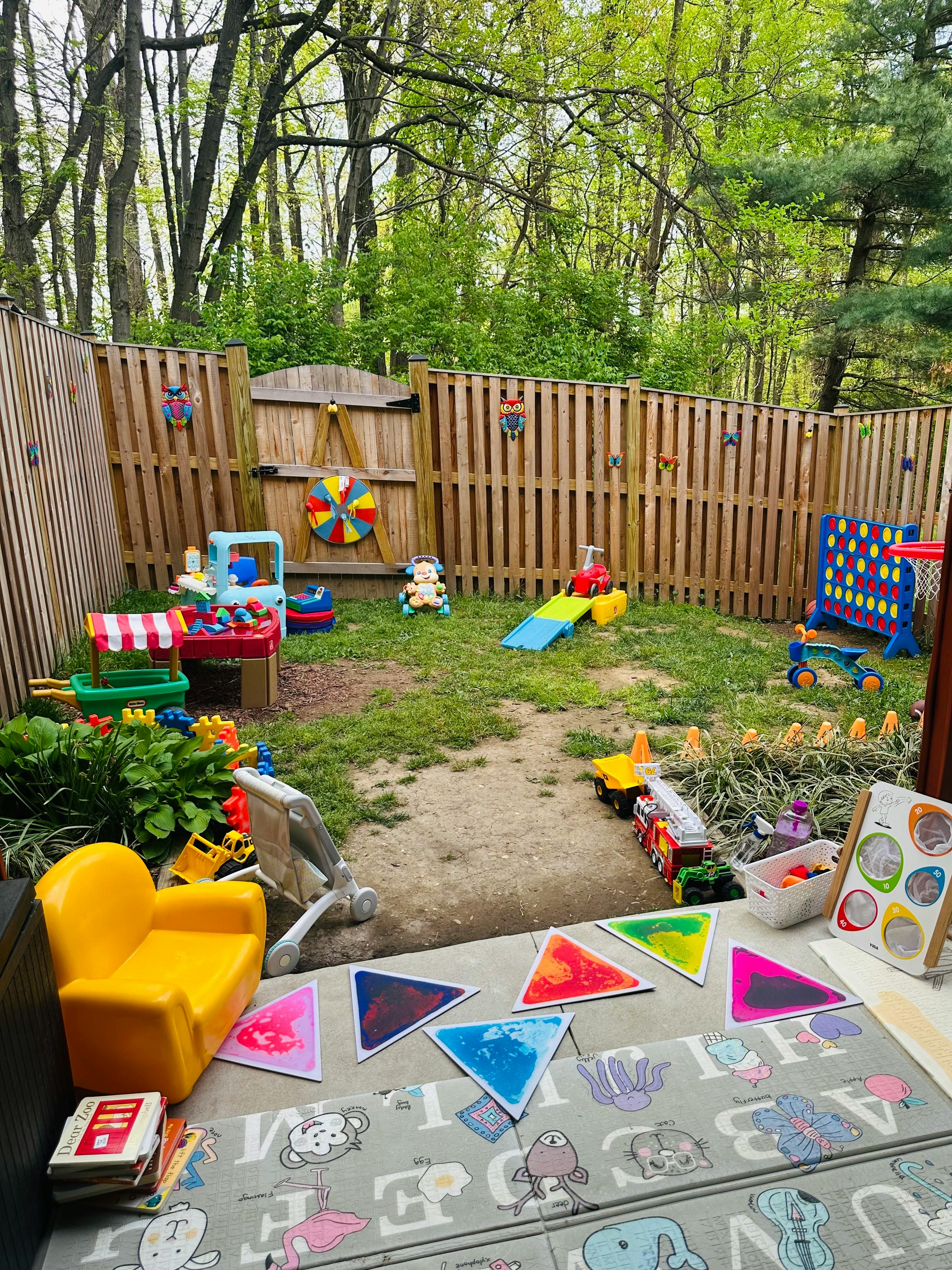 Backyard play area with various toys, including a play kitchen, slide, and large Connect Four game