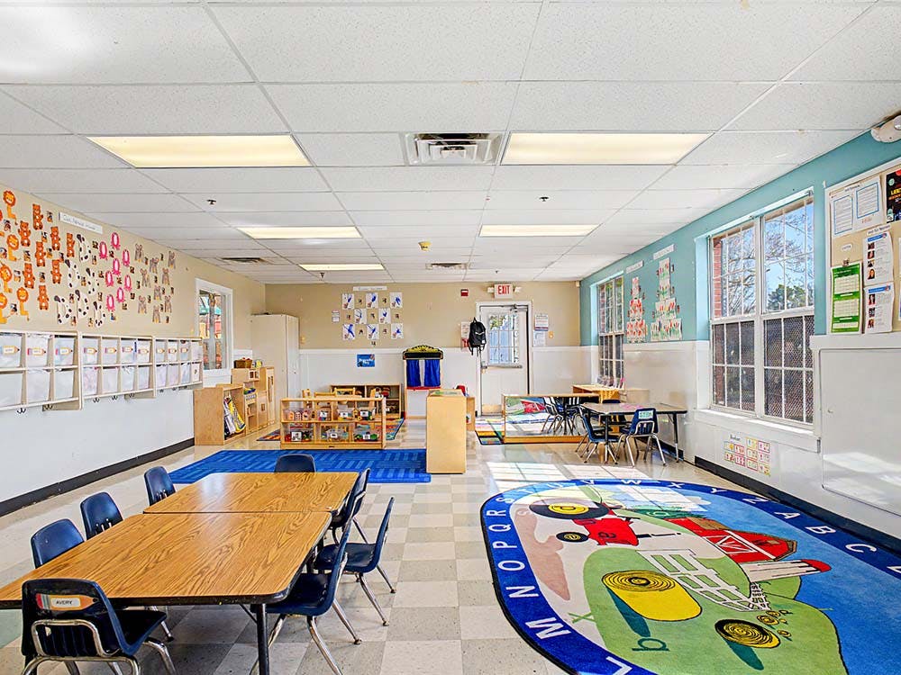 Colorful classroom with child-sized tables and chairs, and decorative rugs