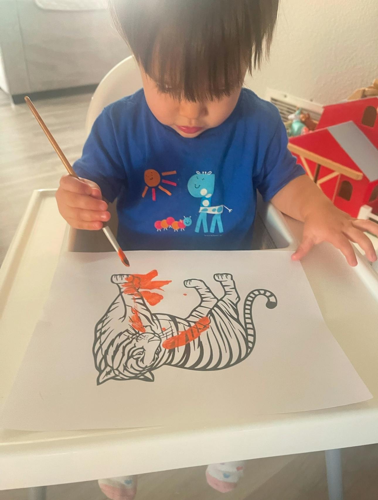 Child painting a tiger drawing with a paintbrush