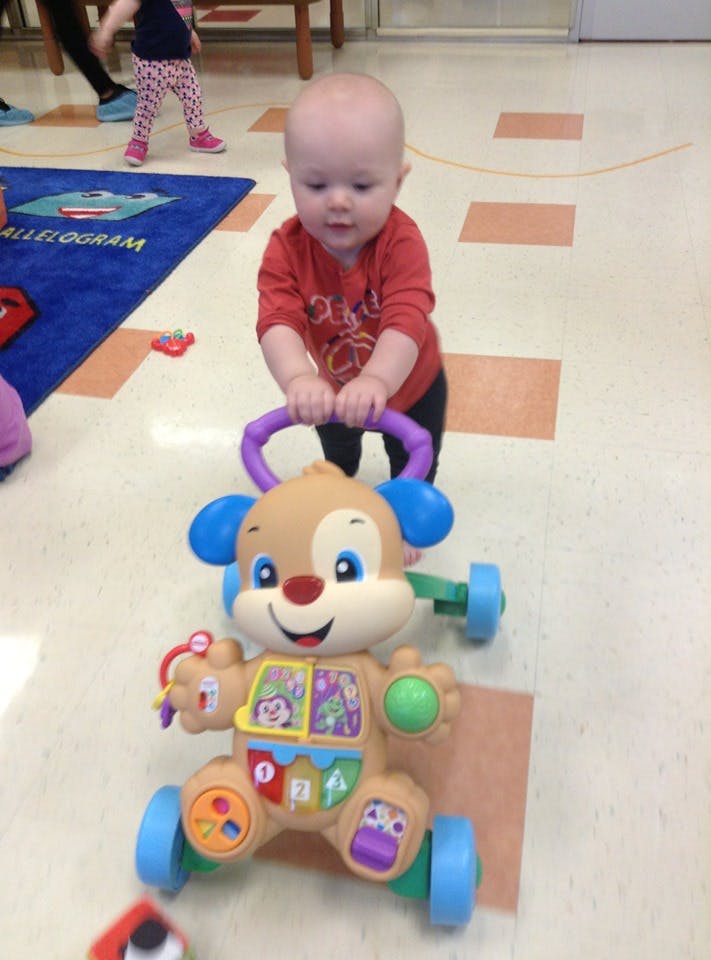 Child standing and pushing a toy dog walker