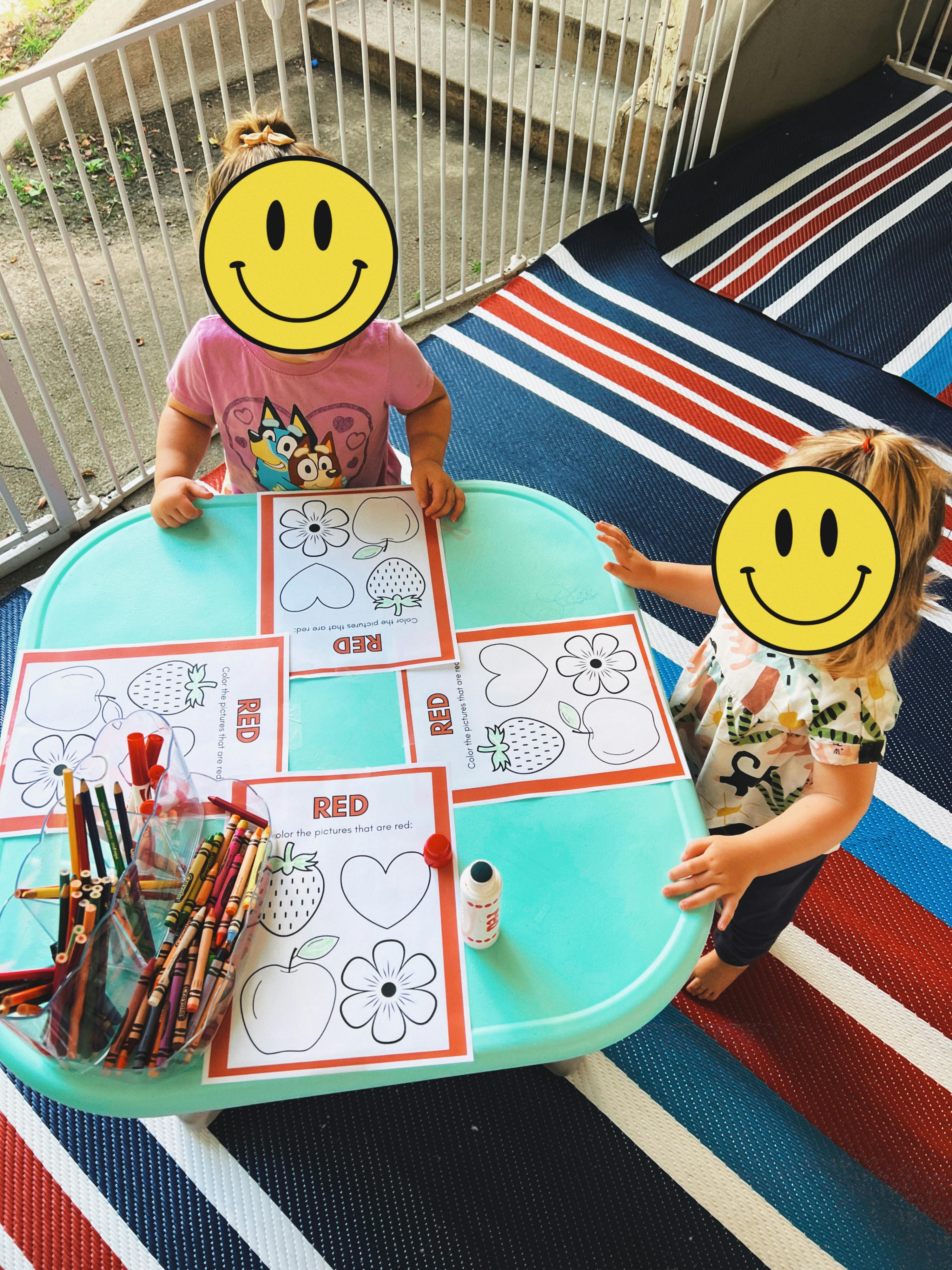 Two children coloring activity sheets at a table