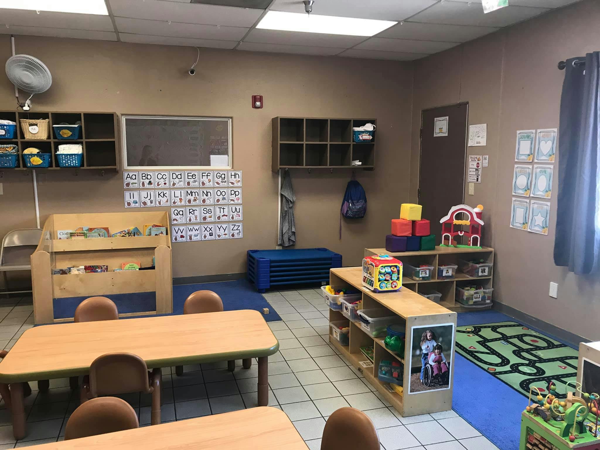 Classroom with tables, chairs, shelves, and educational materials