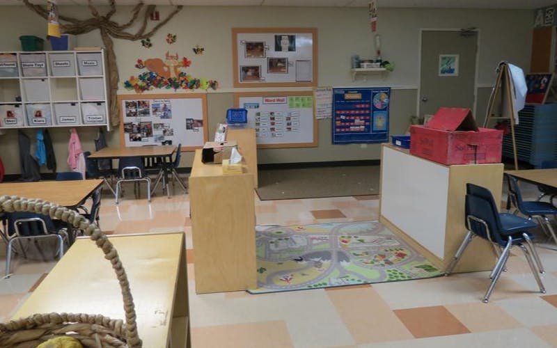 Classroom with tables, chairs, wall decorations, and a playmat