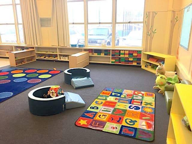 Playroom with colorful rugs, small chairs, and shelves with toys