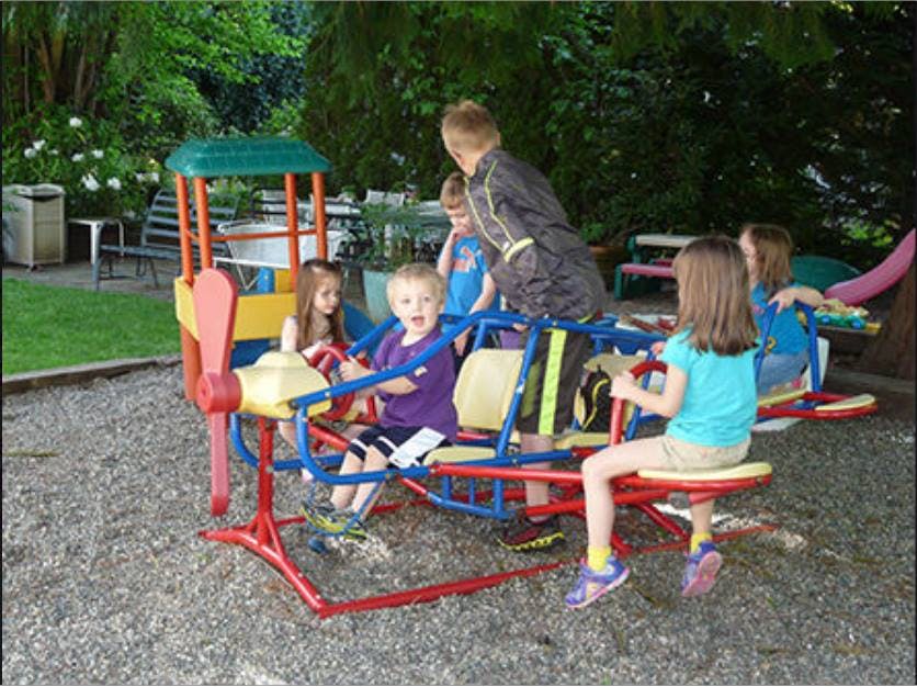 Children playing on a propeller-shaped playground ride