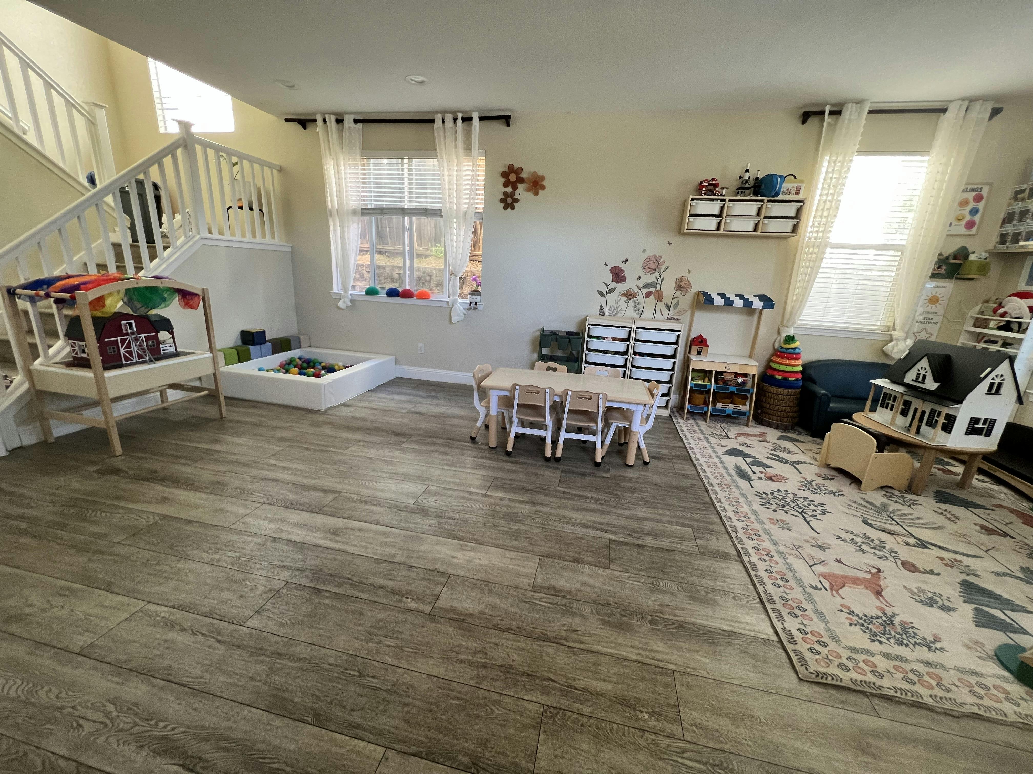 Children's playroom with various toys, a small table with chairs, and a ball pit