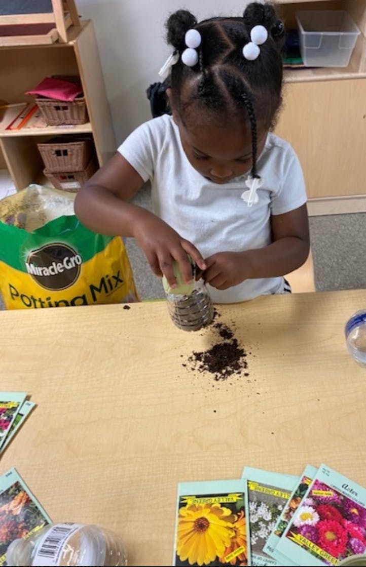 Child pouring potting mix from a bottle onto a table