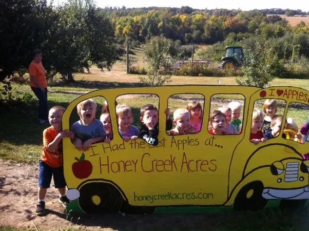 Children in a yellow bus cutout with "Honey Creek Acres" text