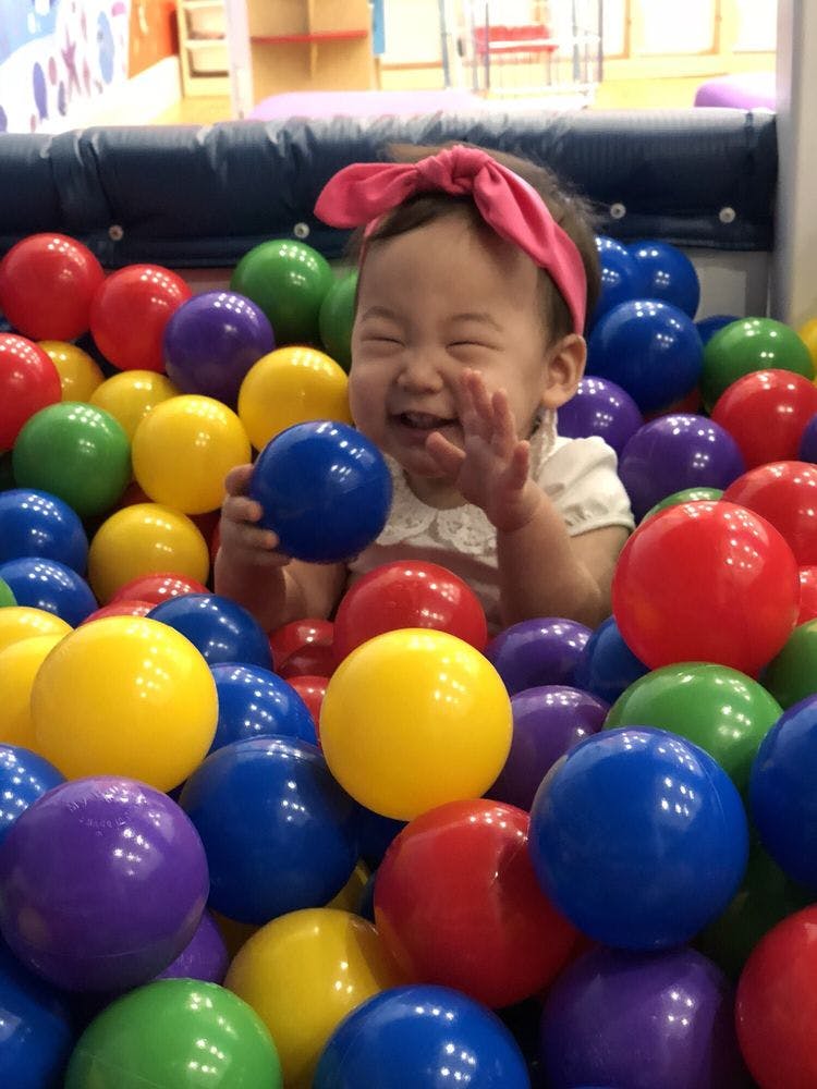 Child in a ball pit holding a blue ball