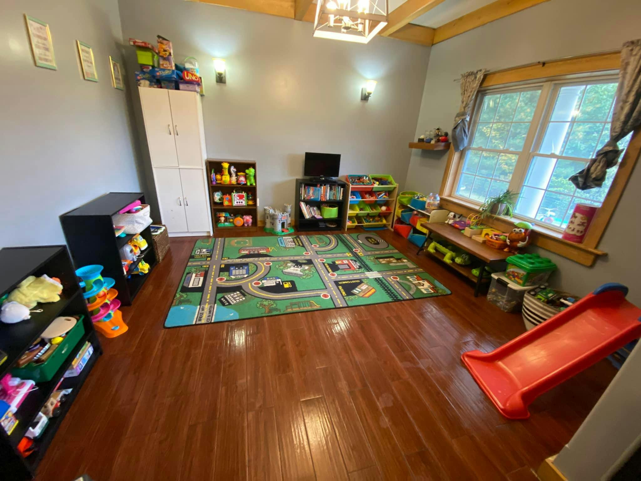 Playroom with a road map rug, toy shelves, and a red slide