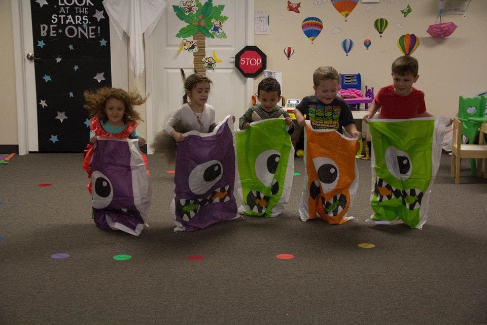 Five children in monster-themed sack race bags for a race
