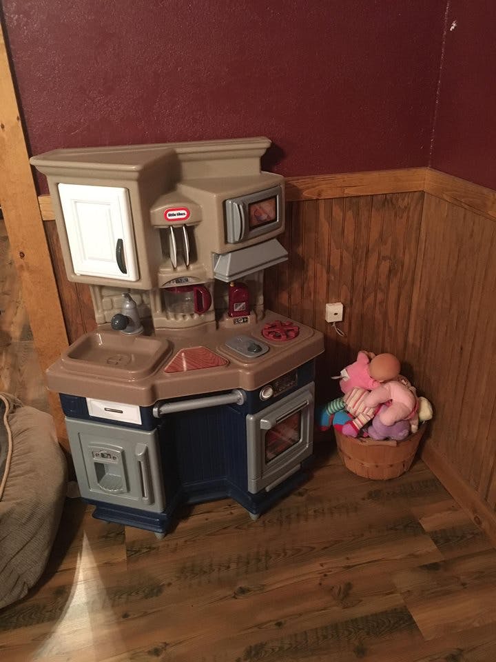 Toy kitchen set with a basket of stuffed animals next to it