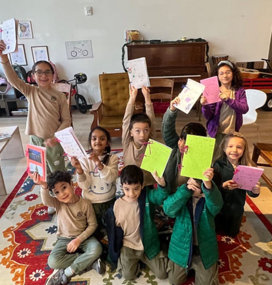 Group of children holding up handmade booklets in a classroom