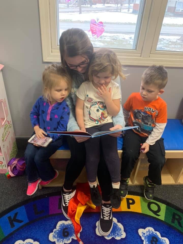 Person reading a book to three children