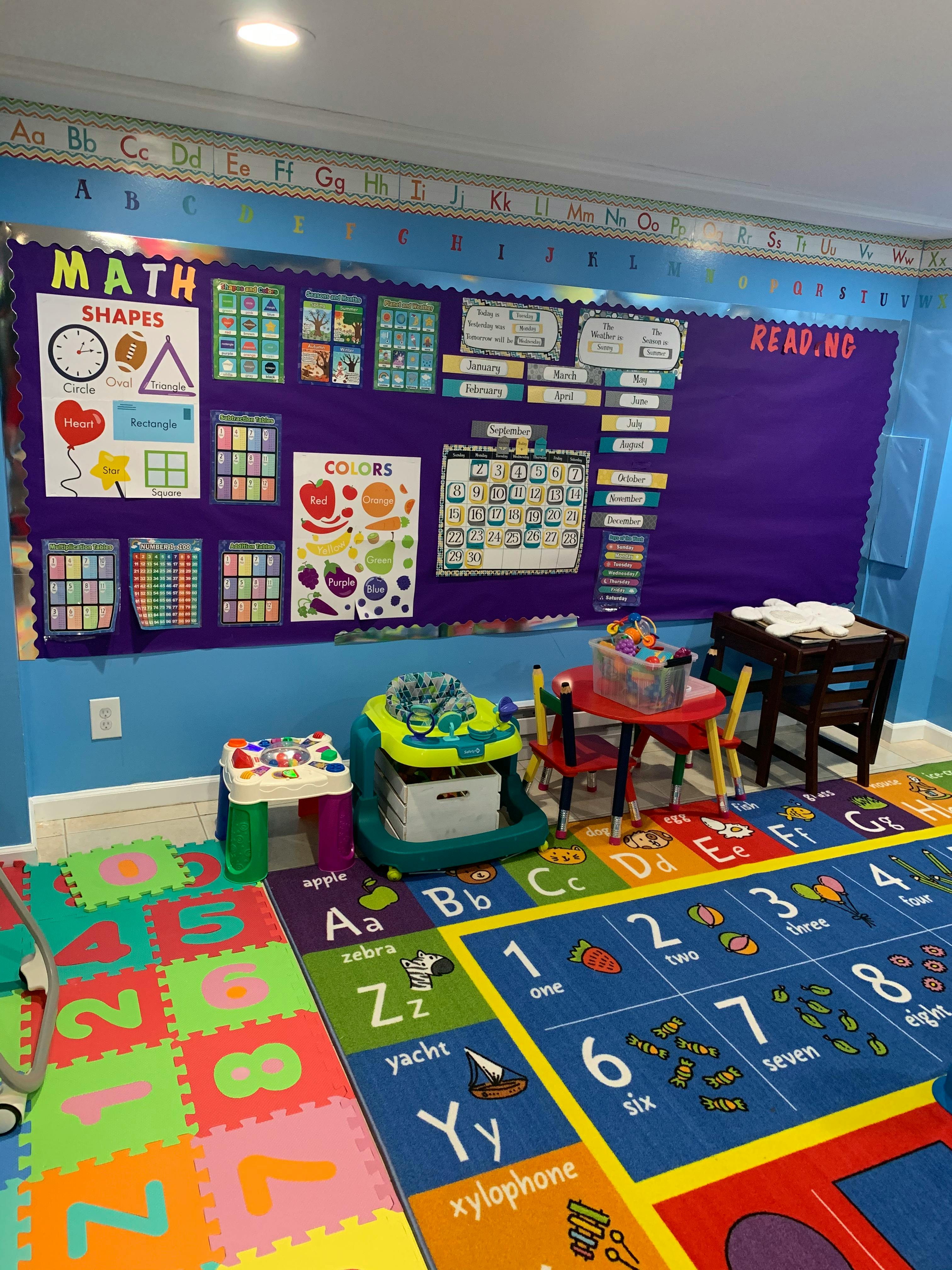 Classroom with learning posters, small tables, and alphabet and number rugs
