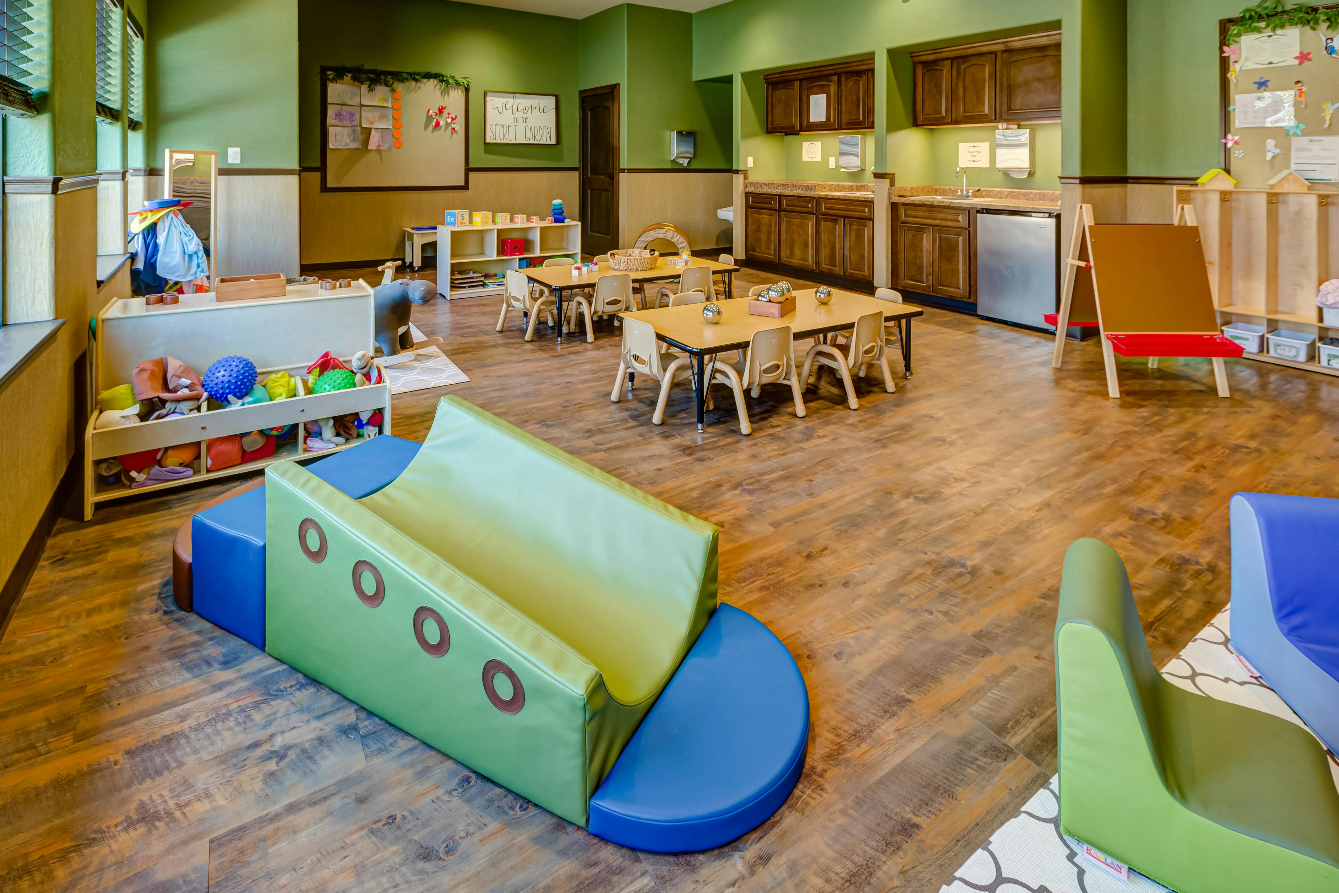 Indoor play area with soft play equipment, small tables, and chairs