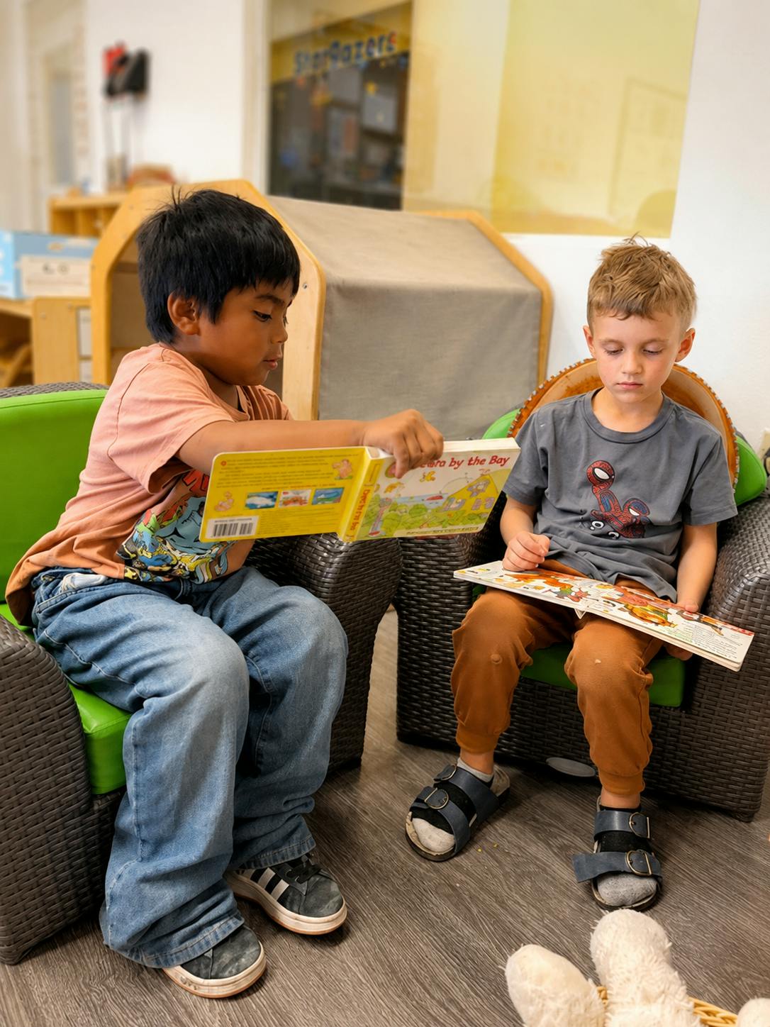 Two children sitting in chairs and reading books
