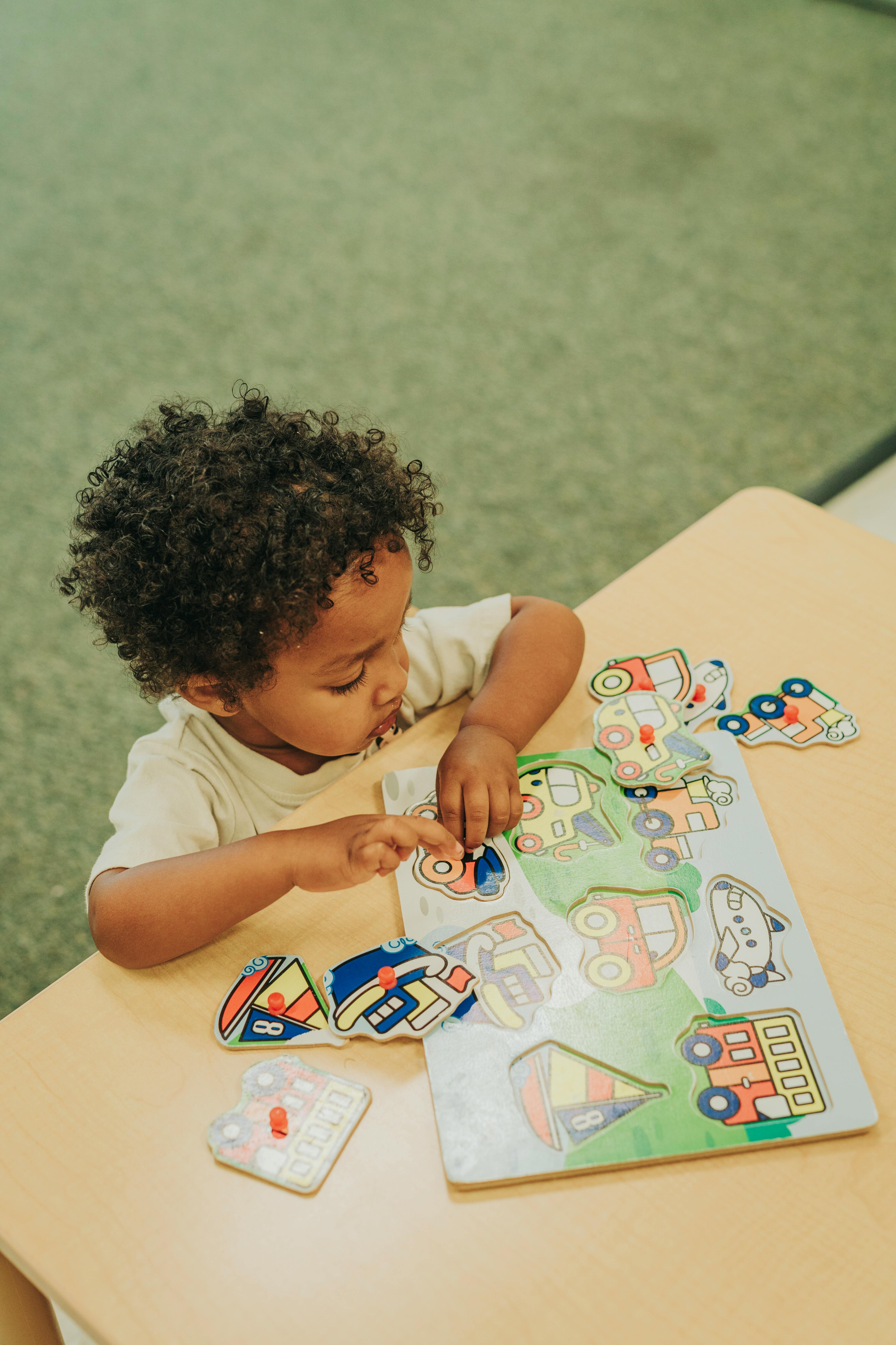Child playing with a vehicle-themed puzzle on a table