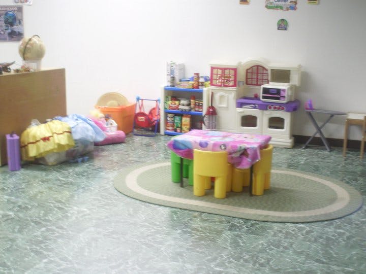 Playroom with small table and chairs, toy kitchen, and shelves of other toys